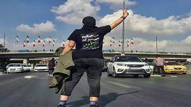 ناشط إيراني يرتدي قميصاً كُتب عليه بالفارسية ""سنقاتل، وسنموت، وسنستعيد إيران" في مدينة كرج